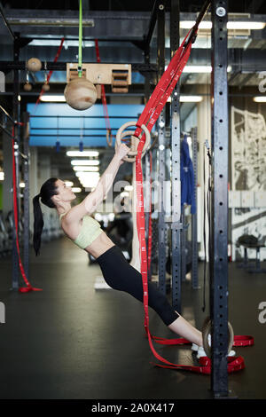 Vue latérale pleine longueur portrait of fit young woman exercising on sonne au cours de l'exercice dans la salle de sport moderne Banque D'Images