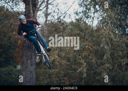 Jeune professionnel sportif cycliste avec vélo BMX faire trick at skatepark Banque D'Images