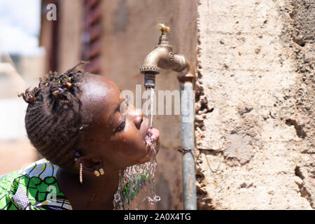 Les gouttes d'eau frais et sain de puiser dans la bouche de l'enfant africain Banque D'Images