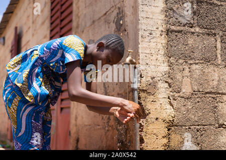 Femme africaine Lave-mains sous Tapez sur l'extérieur Banque D'Images