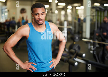 De taille musculaire coach looking at camera tout en se posant en toute confiance dans une salle de sport moderne, copy space Banque D'Images