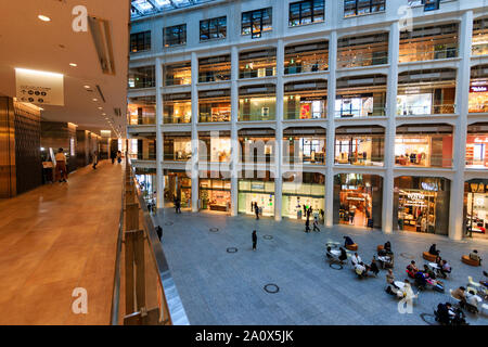 Tokyo, Marunouchi. JP tower KITTE l'intérieur du bâtiment. L'atrium triangulaire, allée, boutiques et rez-de-chaussée coin salon avec des gens assis. La journée. Banque D'Images