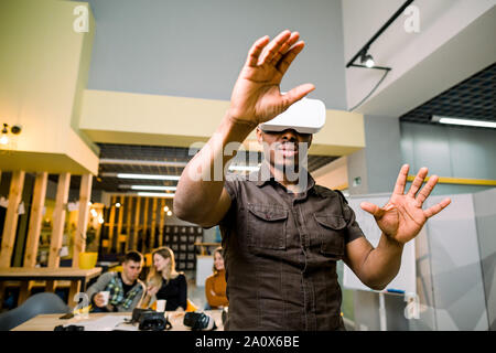 La technologie, les jeux, le divertissement et les gens concept. African man wearing casual et casque de réalité virtuelle ou des lunettes 3D, jeux vidéos Banque D'Images