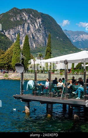 Les gens de manger au restaurant sur la plate-forme au-dessus du lac, le lac de Garde, Riva del Garda, Trentin, Haut Adige, Italie du Nord Banque D'Images