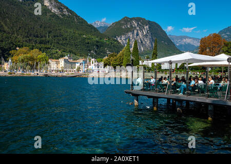 Les gens de manger au restaurant sur la plate-forme au-dessus du lac, le lac de Garde, Riva del Garda, Trentin, Haut Adige, Italie du Nord Banque D'Images