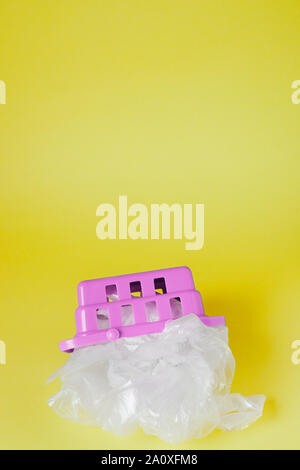 Sacs en polyéthylène dans panier sur fond jaune. Banque D'Images