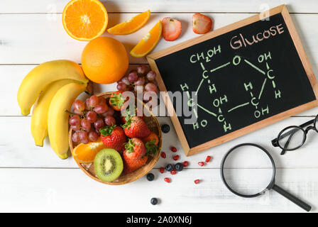 Molécule de glucose sur tableau noir avec un mélange de salade de fruits frais en bois sur fond blanc, l'alimentation et de l'alimentation science concept Banque D'Images