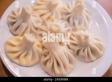 Khinkali dans une assiette blanche. Khinkali avec différentes garnitures de viande et de fromage servi sur un plateau dans un café de style géorgien. Délicieux dîner. La farine de viande et de fromage pr Banque D'Images