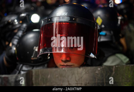 Un agent de police anti-émeute observe tandis que montent la garde pendant la manifestation.encore une semaine, érigent des barricades en feu, brûlé un drapeau chinois et la police a tiré du gaz poivré dans de nouveaux affrontements au cours de griefs par les manifestants anti-gouvernementaux. Banque D'Images