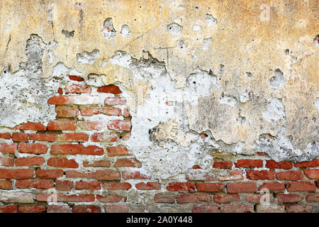 Couche de plâtre fissuré sur mur de brique, les effets de l'humidité du sol sur l'ancien bâtiment maçonnerie Banque D'Images