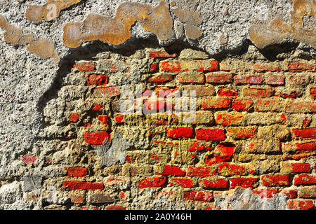 Plâtre fissuré sur mur de brique, la texture sur façade d'immeuble abandonné Banque D'Images