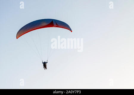 Parapentiste avec un homme haut dans le ciel bleu. Banque D'Images