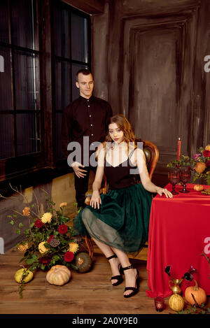 Happy Halloween. Jolie jeune femme et homme de la préparation pour l'Halloween en mettant la table pour un dîner de fête. Banque D'Images
