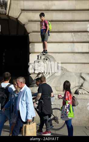 Garçon debout sur la tête de lion en pierre, à Nottingham Banque D'Images