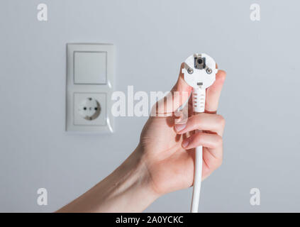 Fiche blanche avec câble dans les hommes de main, prêt à se connecter. Concept de l'énergie. Banque D'Images