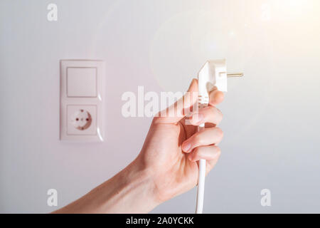 Fiche blanche avec câble dans les hommes de main, prêt à se connecter. Concept de l'énergie. Banque D'Images