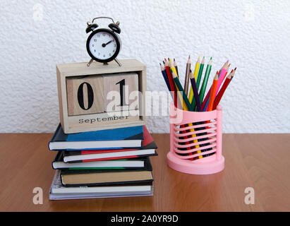 Calendrier en bois avec l'intermittent date de la première de Septembre et d'un réveil, crayons de couleur sur la table, un rappel de l'école, à proximité Banque D'Images