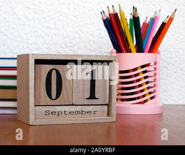 Calendrier en bois avec l'intermittent date de la première de Septembre et d'un réveil, crayons de couleur sur la table, un rappel de l'école, à proximité Banque D'Images