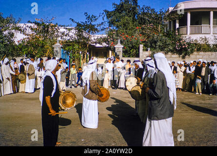 Les hommes arabes célébrant la fin du ramadan à Bahreïn en 1962. Le Ramadan est le neuvième mois du calendrier Islamique, observé par les musulmans du monde entier comme un mois de jeûne, de prière et de réflexion. Banque D'Images