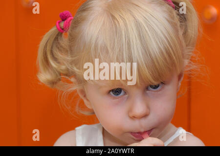 Gros plan portrait d'une adorable jolie mignonne petite fille de deux ans de cheveux blonds vieux avec les yeux bleus et des queues de cochon avec de la paille rose. Banque D'Images