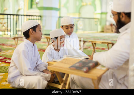 Un enseignant de religion adultes enfants étudiant à l'enseignement à l'intérieur de la mosquée Masjid Sultan, Singapour Banque D'Images