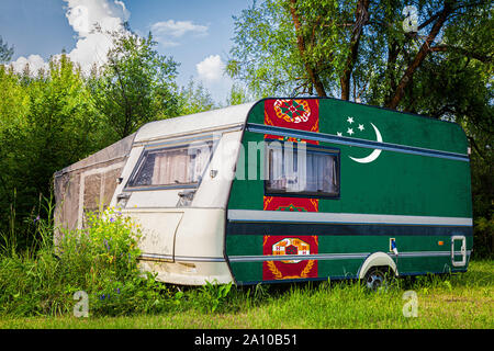 Une voiture remorque, d'une autocaravane, peint dans le drapeau national du Turkménistan est stationné dans une zone montagneuse. Le concept du transport routier, du commerce, de bois de chauffage Banque D'Images