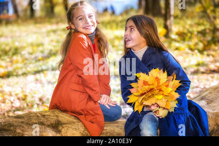 Deux cute smiling 8 ans filles discutent dans un parc sur une journée ensoleillée d'automne. Banque D'Images