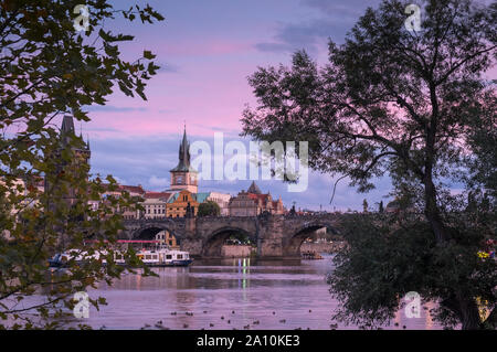 Pont Charles historique et sur les toits de la ville vue à travers le fleuve Vltava au coucher du soleil, Prague, République Tchèque Banque D'Images