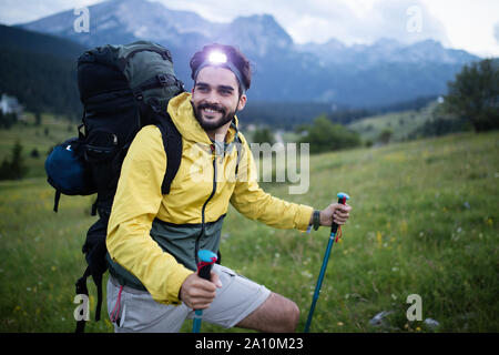 Jeune homme randonneur avec sac à dos et bâtons de marche à la recherche sur les montagnes dans l'air extérieur Banque D'Images