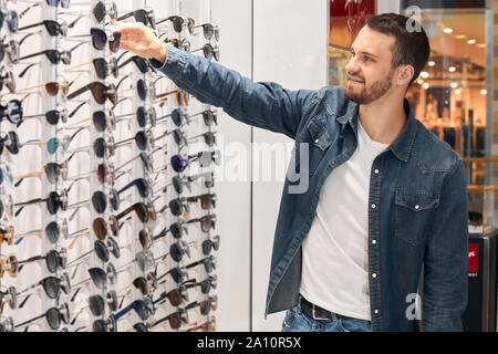 Agréable bonne à la sélection de la clientèle, en tenant les lunettes pour les mettre sur sunglasse . close up side view photo Banque D'Images