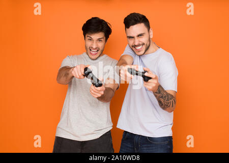 Les joueurs. Deux copains de jeux vidéo, fond orange Banque D'Images