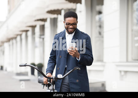 Façon de travailler. Man texting on phone, debout avec le vélo Banque D'Images