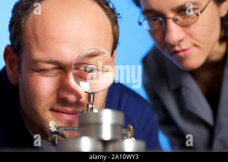 Engineer inspecting détachées par loupe Banque D'Images