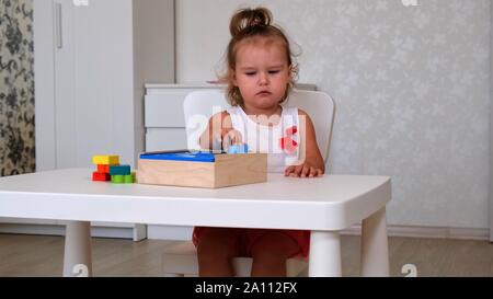 Petite fille, 2 ans, joue les jouets éducatifs, les piles et les chiffres en couleur. L'apprentissage par expérience, les concepts et la motricité fine rugueux Banque D'Images