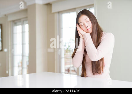 Belle Asian woman wearing sweater occasionnels sur tableau blanc fatigué dormir rêver et posant avec les mains tout en souriant avec les yeux fermés. Banque D'Images