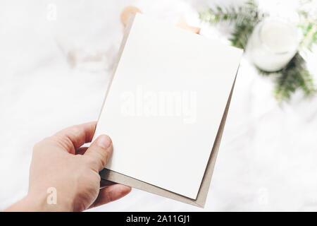 Closeup of woman's hand holding blank carte papier vertical. Carte de souhaits maquette des lieux. Chritsmas design d'hiver. Style Féminin stock photo, floue Banque D'Images