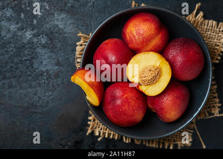 Nectarines mûres fraîches sur fond noir en bois rustique. Top View with copy space Banque D'Images