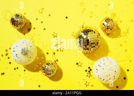 Décorations de Noël blanc et or, miroir, boules disco star sparkles sur fond jaune. Mise à plat, vue du dessus. Nouvelle année minime partie concept. Ch Banque D'Images