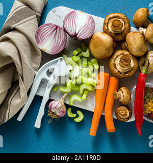 Ingrédients pour la cuisson de légumes curry indien, les citrouilles et les champignons sur un fond bleu et d'épices. tourné à partir de ci-dessus. copy space Banque D'Images