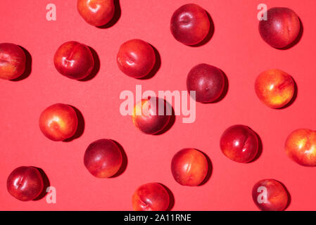 Les nectarines sur fond rouge. Cadre fait de fruits frais. Mise à plat, vue du dessus, copiez l'espace. Régime végétarien et végétalien. Banque D'Images