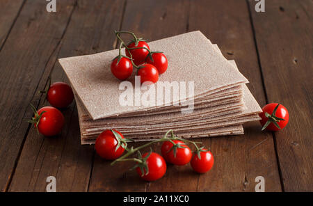 Matières les feuilles de lasagne et tomates cerises sur une table en bois Banque D'Images