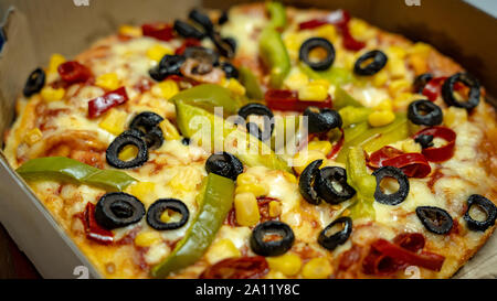 Un gros plan d'une pizza aux olives noires, rouges, de maïs doré et de paprika poivron vert topping Banque D'Images