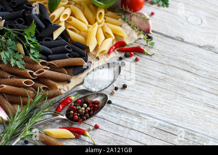 Pâtes penne avec légumes, herbes et huile d'olive sur fond de bois Banque D'Images