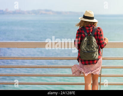 Une jeune femme avec un sac à dos est assis sur le pont à pied près de port d'Alicante Banque D'Images