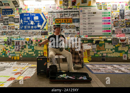 Tai Po, Hong Kong. 23 septembre 2019. Musicien à l'instrument traditionnel chinois en passage souterrain couvert de la démocratie pro affiches et messages dans le Tai Po. Dans la semaine avant le 70e anniversaire de fondation de la République populaire de Chine le 1er octobre, de nombreux soi-disant Lennon murs ont apparu dans la ville et qui sont couverts d'affiches en faveur de la démocratie et de graffitis. Iain Masterton/Alamy Live News. Banque D'Images