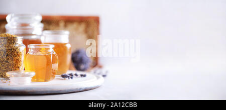 Le miel produits historique. Châssis en nid d'abeille, miel, granules de pollen en pot de verre, l'amande noix sur fond de béton gris. Copier l'espace. Autumn harve Banque D'Images