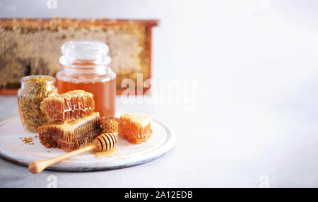 Les granules de pollen d'abeilles, miel pot avec compte-gouttes en bois, de miel sur fond gris. Copier l'espace. Concept la récolte d'automne. Banque D'Images