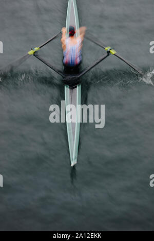 Vue aérienne d'un rameur en skiff bateau sur une eau calme, mi-course, de flou. Banque D'Images