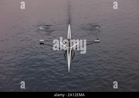 Vue aérienne d'un rameur en skiff bateau sur une eau calme, mi-course, de flou. Banque D'Images
