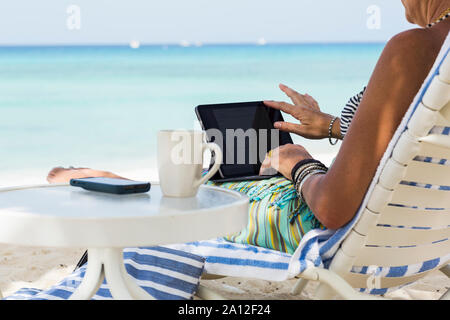 Femme adulte executive en utilisant un ordinateur portable sur la plage, l'île Grand Cayman Banque D'Images